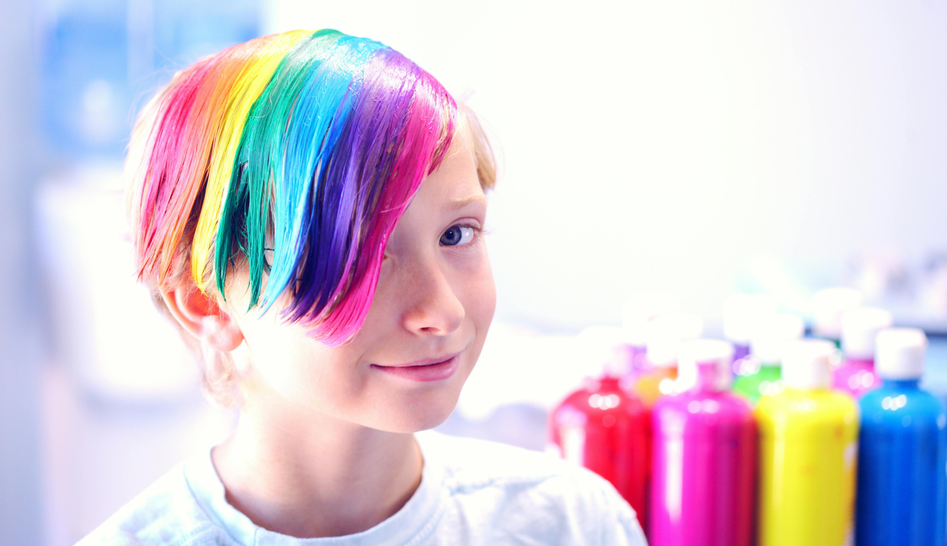 A child with hair dyed in rainbow colours and wearing a white T-shirt