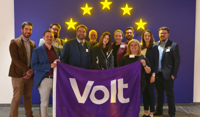 Group of Volters holding a Volt flag in front of European stars