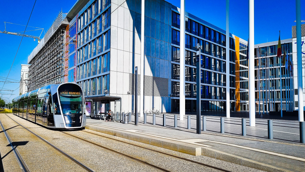 A tram approaching a large building, the European parliament in Luxembourg city