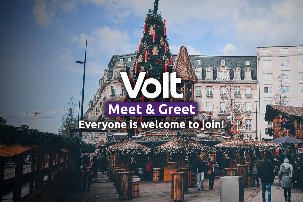 Volt Meet & Greet. Everyone is welcome to join. In the background a big christmas tree and some christmas market huts are seen at the Place de Paris in Luxembourg city.