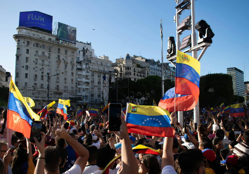 A crowd of people holding up Venezuelan flags and mobile phones